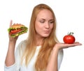 Woman comparing tasty unhealthy burger sandwich in hand and tomato Royalty Free Stock Photo