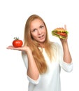 Woman comparing tasty unhealthy burger sandwich in hand and tomato Royalty Free Stock Photo