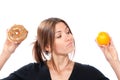 Woman comparing unhealthy donut and organic orange