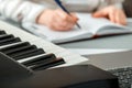 Woman composes music, female hands write notes or song in music book. Teen girl learns to play piano music, makes notes in