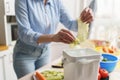 Woman composting food leftovers at home. Female recycling organic waste in a bokashi bin. Person put cabbage leaves in a compost