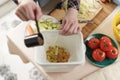 Woman composting food waste at home. Female making a compost with organic food scraps in a bokashi bin. Person put bran into