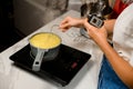 Woman confectioner controls the preparation of syrup with a kitchen thermometer