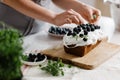 A woman confectioner decorates a delicious cupcake with berries in the kitchen.