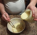 Woman confectioner pour out condensed milk to bowl