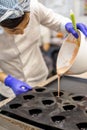 Woman confectioner pouring liquid chocolate into rubber mold tray for cooking pastry candy Royalty Free Stock Photo