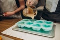 Woman confectioner pouring liquid chocolate into rubber mold tray for cooking pastry candy. Female chef kitchen in Royalty Free Stock Photo