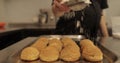 A woman confectioner sprinkles powdered sugar on cookies laid out