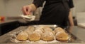 A woman confectioner sprinkles powdered sugar on cookies laid out