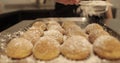 A woman confectioner sprinkles powdered sugar on cookies laid out