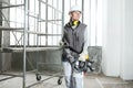 Woman construction worker builder with jackhammer wearing helmet and hearing protection headphones, scaffolding interior