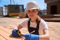 Woman construction worker taking measures of wooden beams with measuring tape Royalty Free Stock Photo