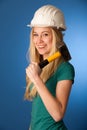 Woman with constructor helmet and hammer happy to do tough work.