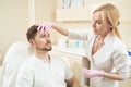 Female beauty therapist squeezing skin on male forehead Royalty Free Stock Photo