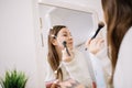 Woman contouring her face using brush and highlighters