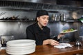 Woman cook checks paid check and cooked dish in kitchen Royalty Free Stock Photo