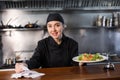 Woman cook checks paid check and cooked dish in kitchen Royalty Free Stock Photo