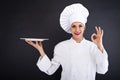 Woman cook or chef serving empty plate and smiling happy