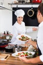 Woman cook giving to waitress ready to serve salad Royalty Free Stock Photo