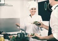 Woman cook giving to waitress ready to serve salad Royalty Free Stock Photo