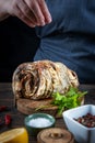 Woman cook holds hand over baked pork with greens on a slate board on a wooden background Royalty Free Stock Photo