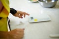 Woman cook power on kitchen scales on table Royalty Free Stock Photo