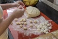 Woman cook sculpts round balls of dough from flour