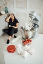 Woman cook sits on the floor against the background of a blender.