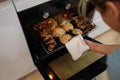 Woman cook taking out baked chicken from oven on baking sheet closeup