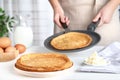 Woman cooking delicious thin pancakes at wooden table