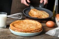 Woman cooking delicious thin pancakes at table