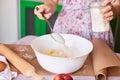 Woman cooking dough for cake. She add sugar, butter and flour into the white bowl on the white table Royalty Free Stock Photo
