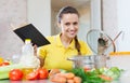 Woman cooking food with cookbook