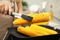 Woman cooking fresh corn cobs on grill pan, closeup Royalty Free Stock Photo