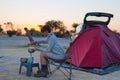 Woman cooking with gas stove in camping site at dusk. Gas burner, pot and smoke from boiling water, tent in the background. Advent Royalty Free Stock Photo