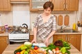 Woman cooking, kitchen interior with fresh fruits and vegetables on the table, healthy food concept Royalty Free Stock Photo