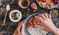 Woman cooking Rice coconut porridge with figs, berries, nuts and coconut milk in plate on rustic wooden background.