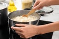 Woman cooking rice on stove in kitchen, closeup Royalty Free Stock Photo