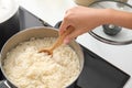 Woman cooking rice on stove in kitchen, closeup Royalty Free Stock Photo