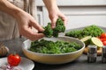 Woman cooking tasty kale salad on table, closeup Royalty Free Stock Photo