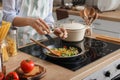 Woman cooking tasty rice with vegetables on stove in kitchen, closeup Royalty Free Stock Photo