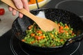 Woman cooking tasty vegetable mix in wok pan at home, closeup Royalty Free Stock Photo