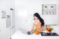 Woman cooking and using laptop in kitchen Royalty Free Stock Photo