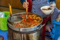 Woman cooking Vietnamese Bun Rieu noodle soup at food vendor