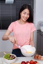 Woman cooking and whisking eggs in a bowl in kitchen Royalty Free Stock Photo