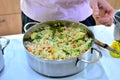 Woman cooks boiled rice with vegetables in a saucepan. Green beans, peppers, corn, peas, onions and carrots are prepared without Royalty Free Stock Photo