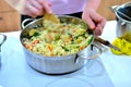 Woman cooks boiled rice with vegetables in a saucepan. Green beans, peppers, corn, peas, onions and carrots are prepared without Royalty Free Stock Photo