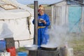 Woman cooks in front of the yurt in steppe, Mongolia.