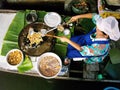 A woman cooks oyster omelette on a boat at the Taling Chan Floating Market in Bangkok