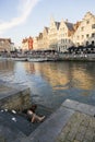 Woman cools het feet on summer evening in river Leie in Ghent